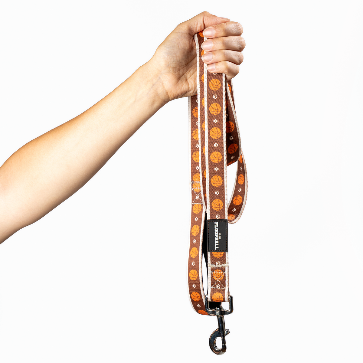 Full-length Floofball basketball dog leash held up to show the padded handle, basketball print and metal clasp.
