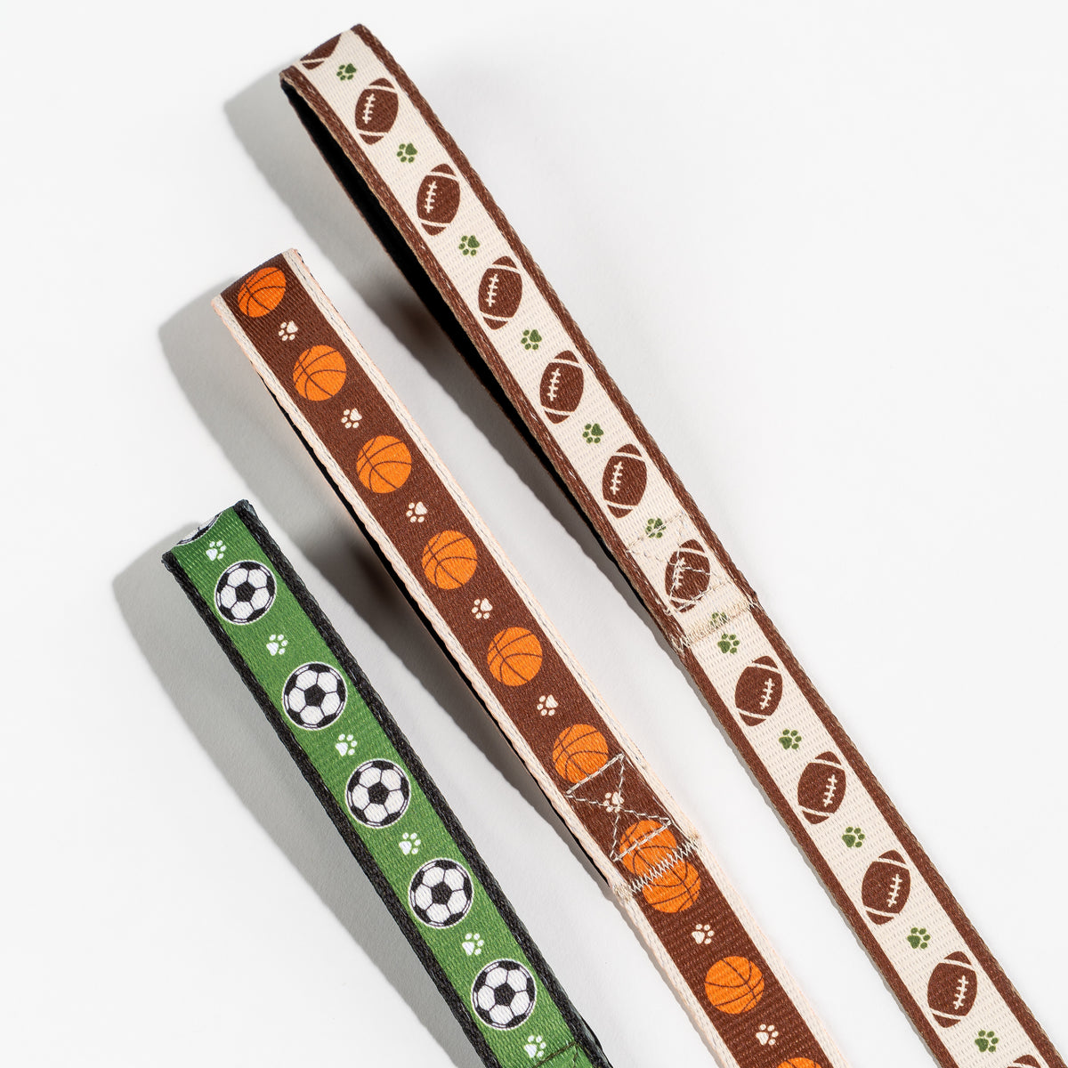Floofball soccer, basketball, and football dog leashes with sport-inspired patterns and paw print details.