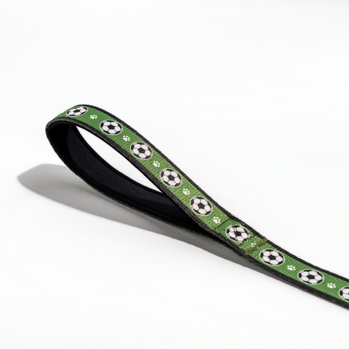 Close-up of the Floofball soccer dog leash padded handle with black lining and green soccer ball pattern.
